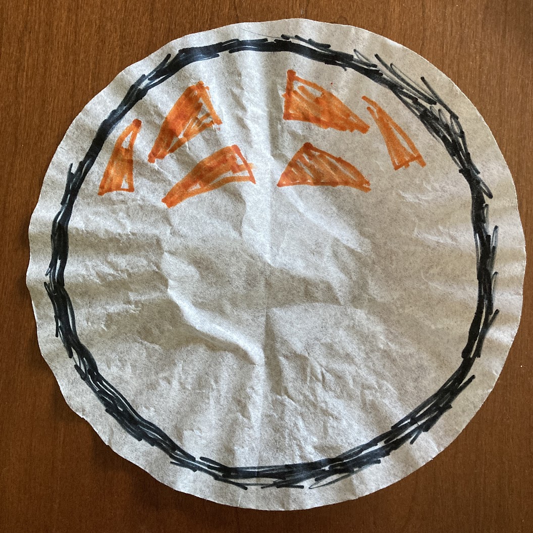 A coffee filter with a 6 triangles arranged in a symmetrical pattern with sketchy black circle drawn around the outside 