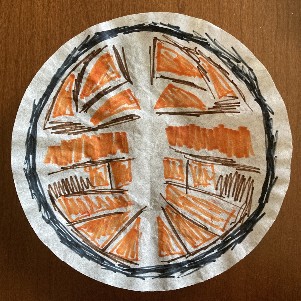 A coffee filter colored with marker showing a symmetrical orange and brown pattern surrounded a sketchy black circle around the outside.