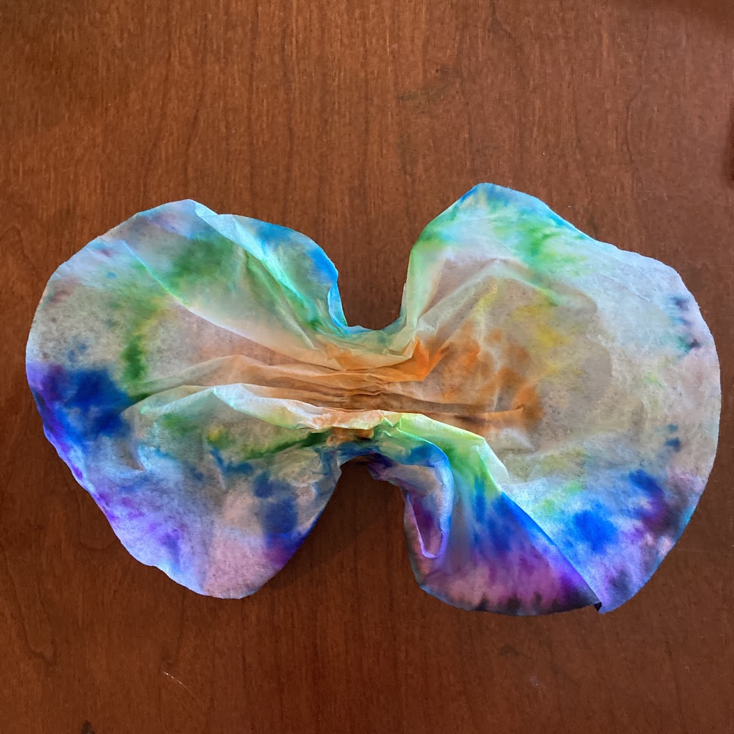 A tie-dyed coffee filter pinched in the middle to make two butterfly wings.