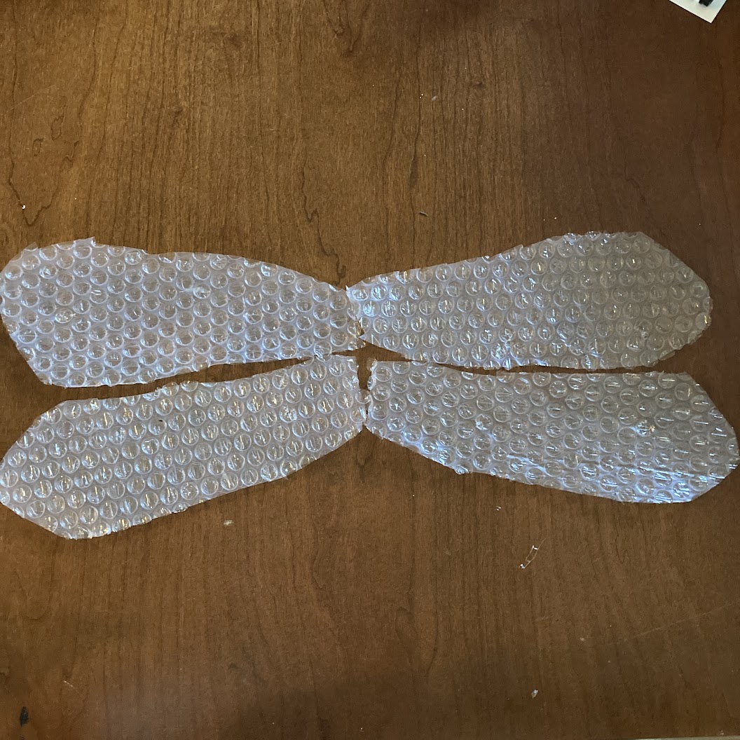 Four pieces of bubble wrap cut and arranged like dragonfly wings.
